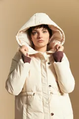 Campera acolchada de nylon en color crema, con capucha ajustable, cierre frontal con botones y cordón de ajuste en la cintura.