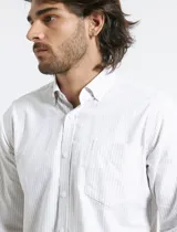 Camisa de manga larga con estampado de rayas verticales finas en color azul y blanco. Presenta cuello button-down, cierre frontal con botones nacarados y un bolsillo en el pecho.