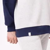 Buzo de estilo deportivo con cuello polo y cierre frontal de botones. Presenta un diseño de bloques de color en gris, blanco y azul marino, con mangas largas y puños elásticos. Incluye logo bordado en el pecho.