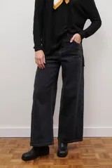 Jean de denim negro con corte ancho, holgado y tiro alto. Se destaca por sus pespuntes en zigzag de color naranja.