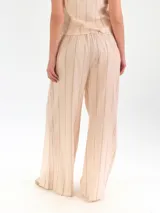 Pantalón de lino color beige, de corte ancho y relajado, con pretina elástica y cierre de botón.