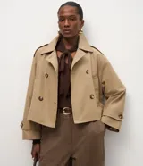 Trench coat corto de la marca Cortelle, confeccionado en una mezcla de algodón y poliéster con estructura de lona. Presenta un diseño de abotonado cruzado, cuello clásico, mangas largas con trabillas en los puños y bolsillos frontales.