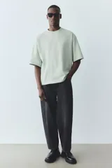 Remera verde claro de algodón pesado, corte oversized, con cuello redondo ribeteado, hombros caídos y bajo recto.