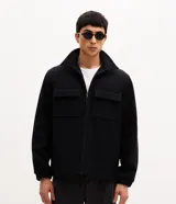 Campera pesada tipo trucker de Marfinno, confeccionada en polivelour negro. Presenta cuello camisero, cierre frontal con cremallera y dos bolsillos frontales con solapa en el pecho.