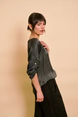 Blusa holgada de satén color beige, con escote en V y mangas largas con trabilla para sujetar remangadas.