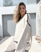 Sweater de punto en color crudo con detalles de costuras y bordes en color negro. Presenta un diseño de corte holgado, cuello redondo y mangas largas con puños acanalados.