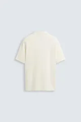 Polo negro de manga corta con cuello solapa y abertura frontal. Presenta un tejido jacquard con textura geométrica sutil.