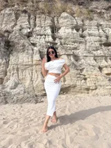 Conjunto de dos piezas compuesto por un top de escote bote y una falda midi, ambos confeccionados en tela bambula elastizada de textura arrugada.