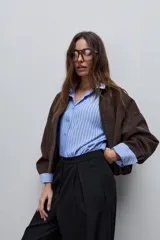 Pantalón marrón de tiro alto y silueta amplia, confeccionado con pinzas en el frente y bolsillos laterales.