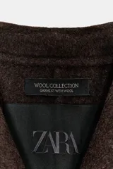 Blazer oversize de Zara Woman Collection confeccionado en mezcla de lana, con cuello sin solapa, manga larga y cierre frontal con botón. Presenta bolsillos delanteros con solapa.