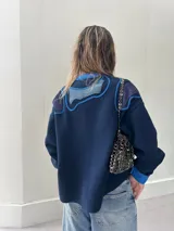 Campera azul marino con apliques de tela azul en los hombros y en el frente, con botones al frente y puños celeste.
