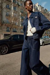 Chaqueta estilo bomber de Zara confeccionada en tejido denim azul oscuro. Presenta cuello solapa, cierre frontal con cremallera, bolsillos delanteros con solapa y bajo elástico que le otorga un ajuste ceñido en la cintura.
