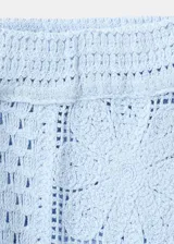 Pantalón tejido de punto celeste con diseño calado de flores, de corte recto y tiro medio con cintura elástica.