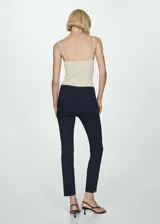 Pantalón de vestir azul marino de corte ajustado y tobillero, con bolsillos laterales, trabillas para cinturón y cierre frontal con cremallera y botón oculto. Presenta pequeñas aberturas en los bajos.