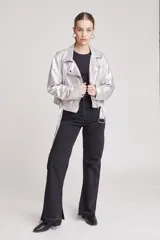 Cazadora estilo biker metalizada en color plateado, con cierre frontal asimétrico, solapas con broches a presión, mangas largas con cierre en los puños y cinturón ajustable en el ruedo.