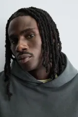 Sudadera tipo hoodie de color blanco hueso, con capucha, manga larga y bolsillo canguro frontal. Presenta un calce relajado y tejido de algodón con interior afelpado.