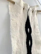 Tapiz decorativo de fieltro artesanal en lana merino uruguaya, con diseño abstracto en blanco y negro.