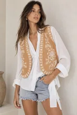 Chaleco beige con diseño bordado en hilo blanco con motivos florales y geométricos.
