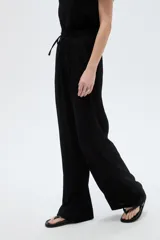 Pantalón negro de poliéster, con bolsillos laterales, tiro alto y diseño ancho.