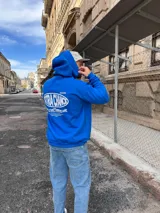 Canguro azul francia con capucha, confeccionado en algodón. Presenta un diseño gráfico estampado en la espalda con el texto 'EXTRA CHANCE' y frases motivacionales en color blanco.