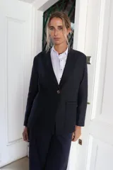 Blazer femenino forrado de corte tradicional, levemente entallado en la cintura, con mini hombreras. Presenta un botón metálico decorativo con escudo y costuras en tono contraste.