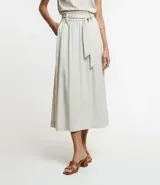 Pollera midi de corte clochard confeccionada en mezcla de viscosa y lino. Presenta cintura elástica con lazo ajustable del mismo tejido, bolsillos laterales y una caída fluida.