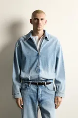 Cazadora de denim de algodón con efecto lavado, corte cropped, cuello solapa, cierre frontal con cremallera de doble dirección, manga larga con puños abotonados y bolsillos laterales.