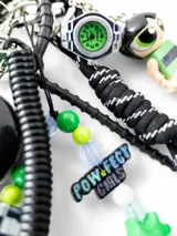 Llavero con aro metálico plateado, colgante de plástico verde con inscripción "ID CASE" y fecha, cordones amarillo y turquesa, dije de conejo de peluche con zanahoria y cordón blanco y negro.