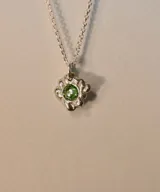 Collar plateado con dije en forma de estrella con piedra verde engarzada.