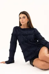 Blusa de manga larga en color azul marino, confeccionada en tejido plisado con detalles de volados horizontales a lo largo de toda la prenda.