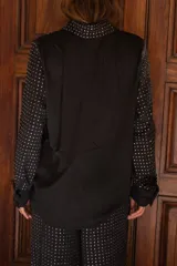 Camisa de manga larga color negro con apliques de strass plateados distribuidos en todo el diseño. Presenta cuello clásico, cierre frontal con botones y puños abotonados.