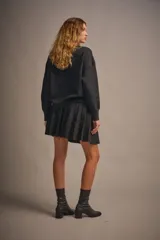 Sweater tejido color marrón claro, de escote redondo y calce holgado. Tiene hombros caídos, mangas largas y puños tejidos.