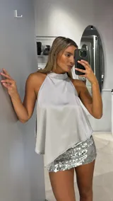 Top de satén con cuello halter, diseño holgado y corte asimétrico.