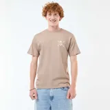 Camiseta de algodón color beige con cuello redondo y manga corta. Presenta un pequeño estampado frontal de una calavera con sombrero de paja y huesos cruzados.