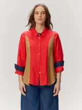 Camisa de lino combinada en color rojo con paneles frontales en tono tostado y detalles en azul oscuro en el cuello y puños vueltos. Presenta cierre frontal con botones y mangas largas.