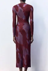 Vestido midi de microtul con diseño drapeado lateral, cuello alto y mangas largas. Presenta un estampado tipo tie-dye en tonos bordó y violeta.