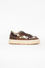 Championes urbanos confeccionados en cuero con detalles en tonos marrones y pelo con estampado animal print tipo vaca, cordones y suela robusta color tostado.