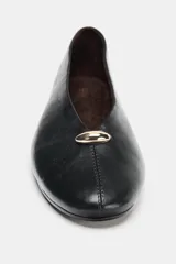 Bailarina plana de piel negra con acabado suave, escote en pico y detalle metálico dorado en la parte frontal. Presenta pespuntes decorativos y punta redonda.