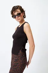 Musculosa blanca de tejido acanalado con detalle de trenzado lateral ajustable.