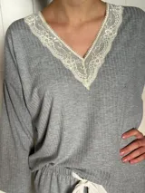 Pijama de algodón gris con textura acanalada, compuesto por una remera de escote en V decorado con puntilla y un pantalón recto con elástico y lazo en la cintura.
