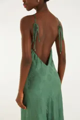 Vestido largo verde con estampado sutil de conchas marinas, escote halter y tirantes finos. Presenta un diseño fluido y silueta recta con escote en la espalda.