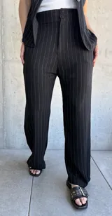 Pantalón negro de vestir con finas rayas verticales blancas, corte recto y tiro alto.