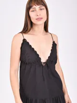 Vestido corto negro con breteles finos, escote en V con detalle de puntilla y falda con volado y calado.