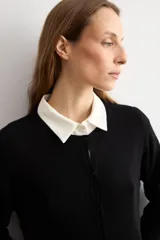 Cardigan de punto fino color negro, con cuello redondo, cierre frontal de botones y mangas largas.