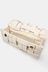 Bolso de mano de formato alargado en color marfil, con diseño de efecto trenzado y asa metálica dorada en el frente. Cuenta con cierre mediante doble clip metálico.