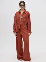 Camisa azul de corte holgado, con cuello camisero, mangas largas con detalles en los puños, bolsillo frontal con bordado y cierre delantero con botones.