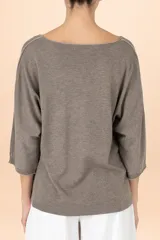 Suéter de punto color gris con cuello en V, manga tres cuartos y detalle de costura central vertical. Presenta un diseño de silueta holgada y terminaciones acanaladas en puños y ruedo.