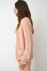 Chaqueta tejida color nude con botones metálicos y textura de punto.