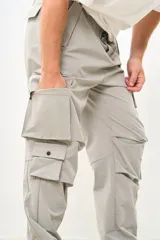 Pantalón cargo color gris claro, de corte amplio, con múltiples bolsillos con solapa y ajuste con cordón en la cintura.