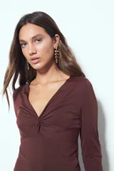 Top de manga larga color negro con escote en V y detalle de frunce central. Presenta un corte entallado que se adapta a la figura.